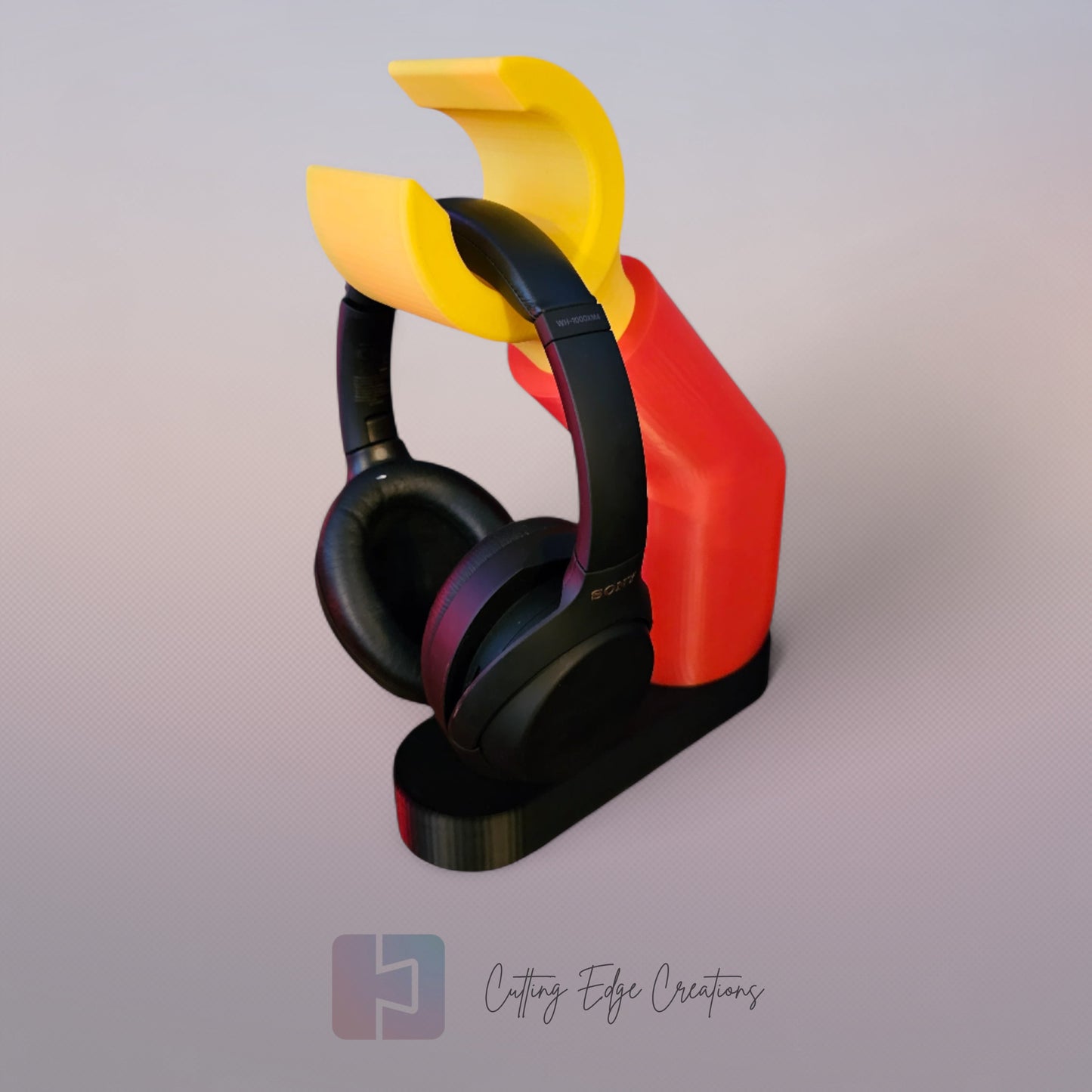 3D printed block style arm in various colours, with black base for wall or freestanding mounting, with chunky yellow hand to hold headphones or coats