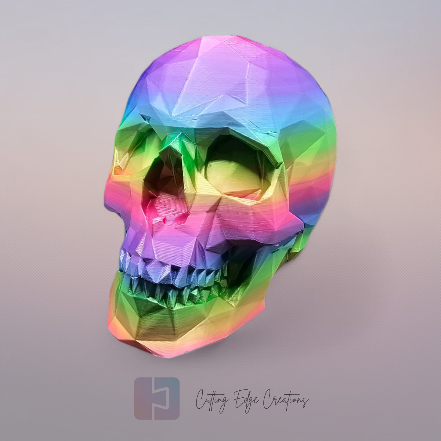 3D-printed low-poly rainbow skull figurine, uniquely coloured with a vibrant gradient. Handmade in the UK, 12cm tall, and perfect for modern home decor or gothic-inspired interiors