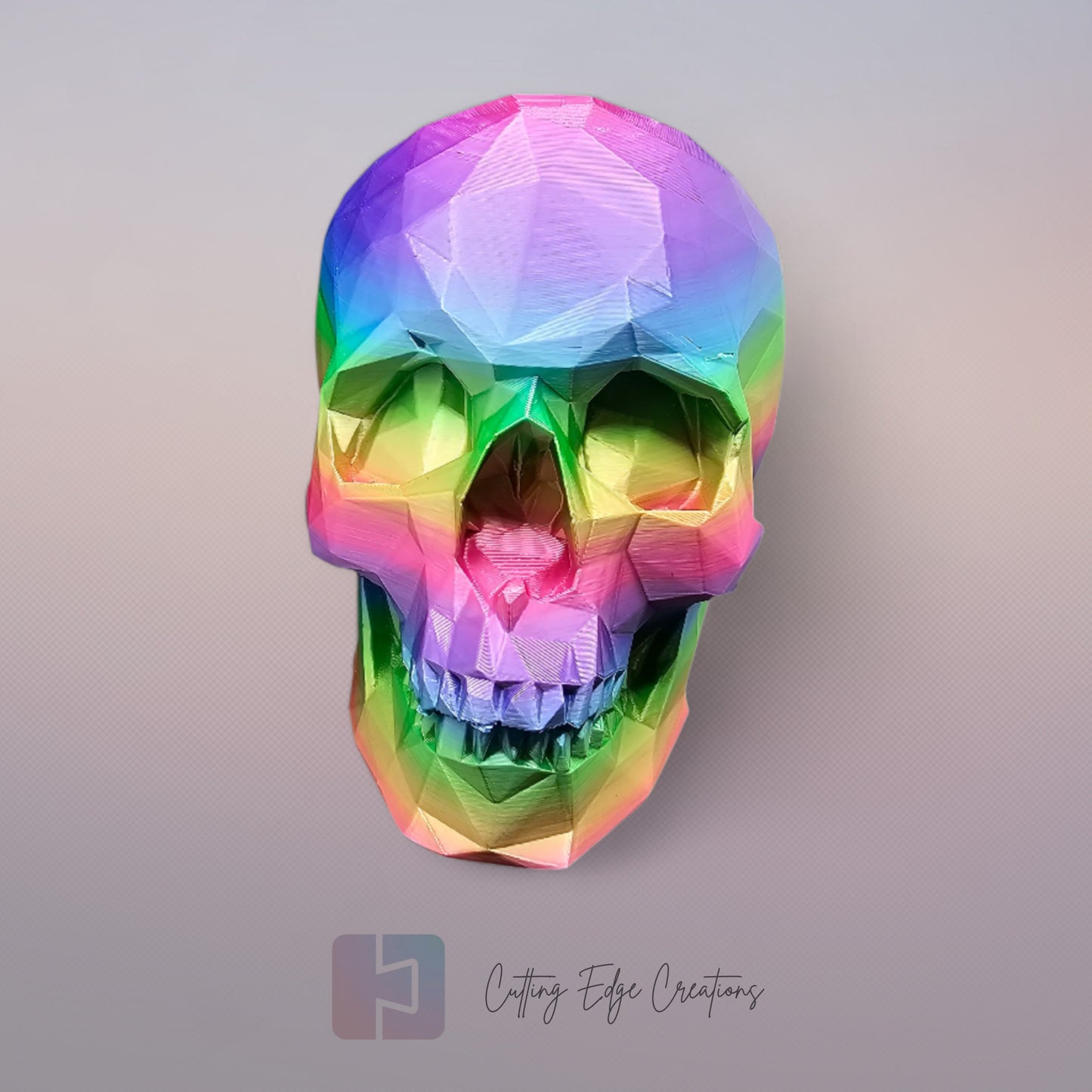 3D-printed low-poly rainbow skull figurine, uniquely coloured with a vibrant gradient. Handmade in the UK, 12cm tall, and perfect for modern home decor or gothic-inspired interiors