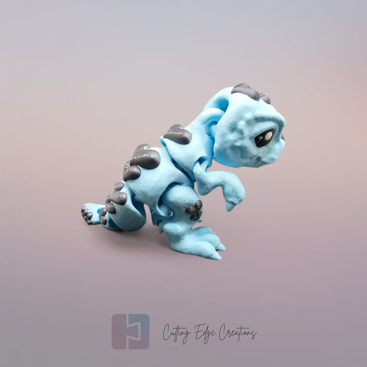 3D printed Love O’Saurus Rex dinosaur toy in light blue with black heart-shaped markings, designed as a flexible and posable fidget toy. Made in the UK by Cutting Edge Creations