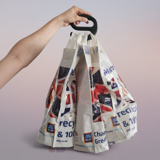 A strong black plastic handle holding multiple Aldi shopping bags in one hand against a white background.