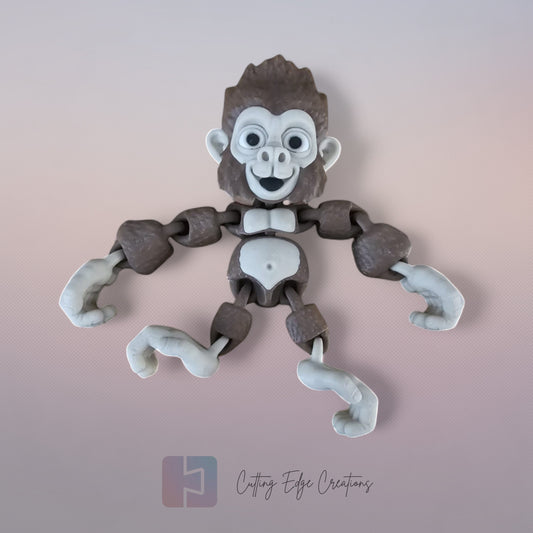 3D printed articulated Mega Gorilla toy hanging upside down from black poles in a garden, with hook-shaped hands and feet, surrounded by lush green bamboo leaves.