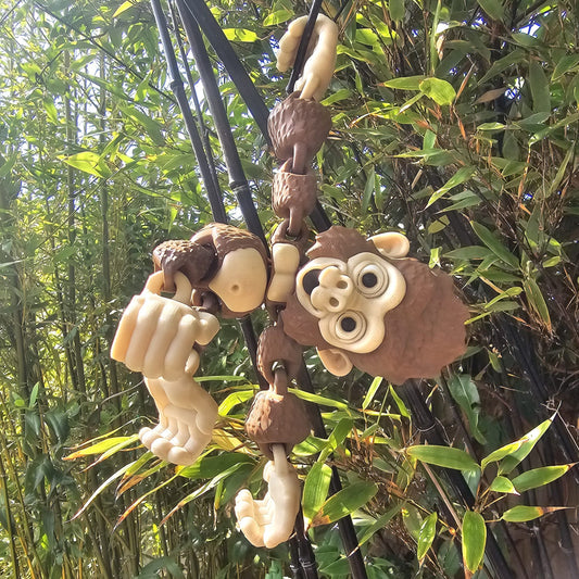 3D printed articulated Mega Gorilla toy hanging upside down from black poles in a garden, with hook-shaped hands and feet, surrounded by lush green bamboo leaves.