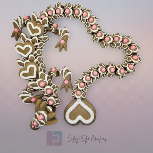 3D printed cookie style articulated dragon with pink and white icing details