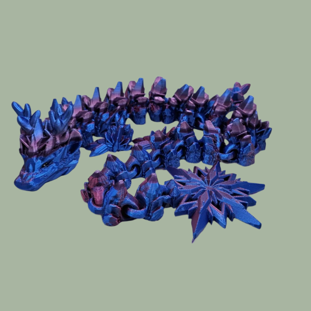3D printed articulated dragon with snowflake details and large snowflake on tail, in a blue/purple/pink colour