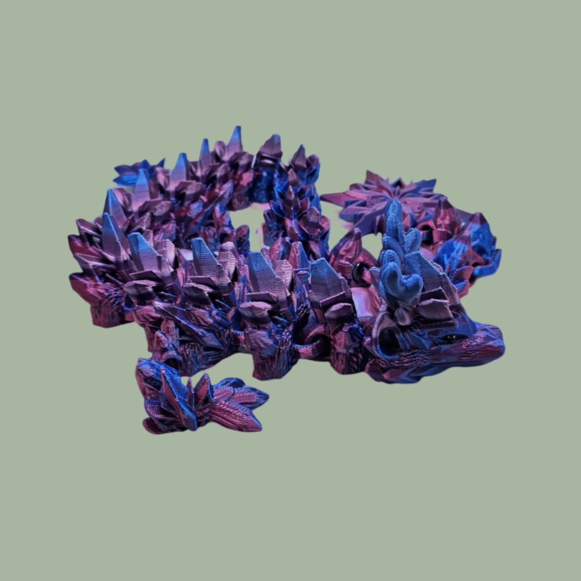 3D printed articulated dragon with snowflake details and large snowflake on tail, in a blue/purple/pink colour