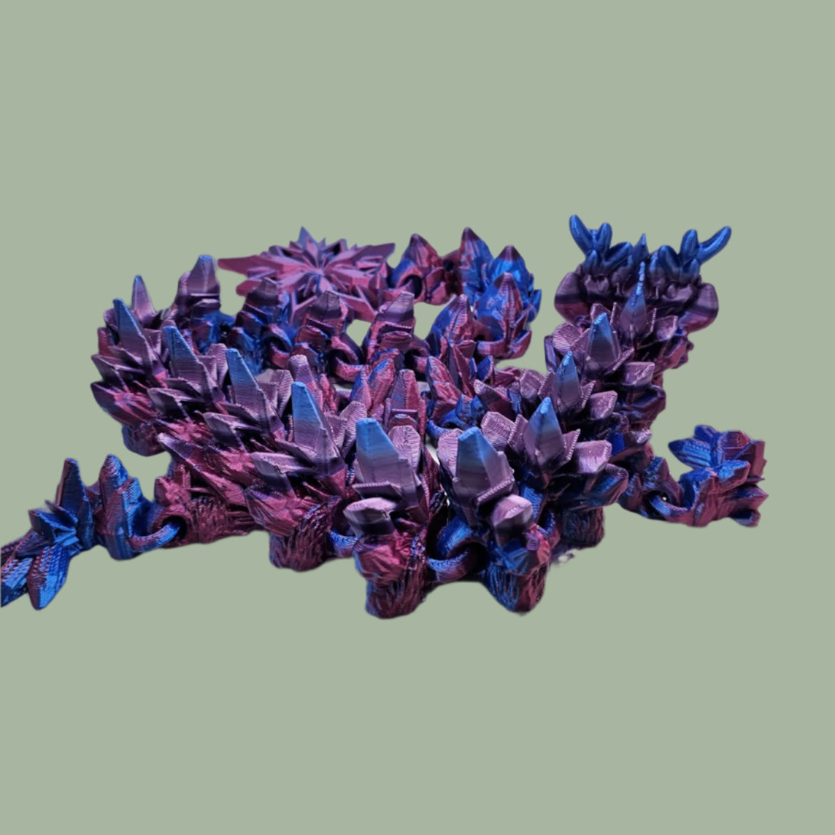 3D printed articulated dragon with snowflake details and large snowflake on tail, in a blue/purple/pink colour