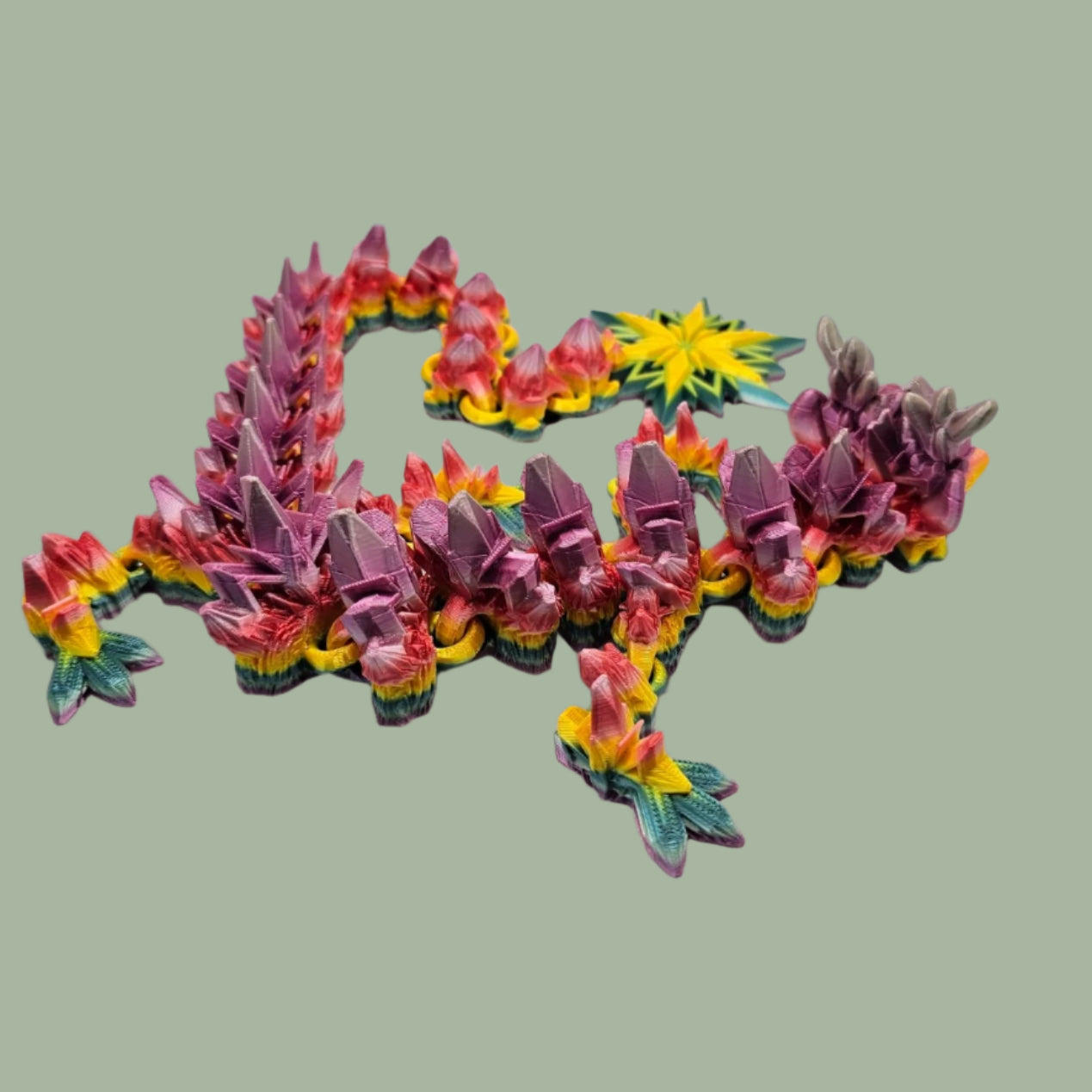 3D printed articulated dragon with snowflake details and large snowflake on tail, in a rainbow colour