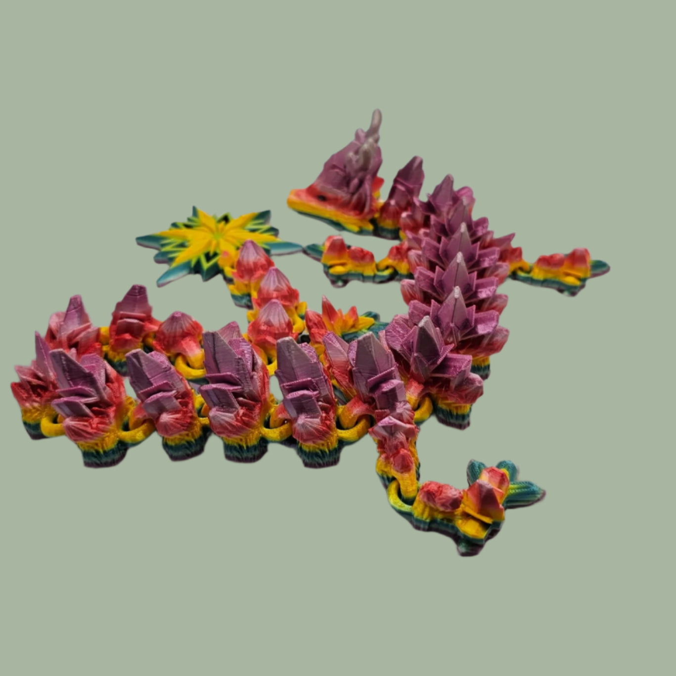3D printed articulated dragon with snowflake details and large snowflake on tail, in a rainbow colour