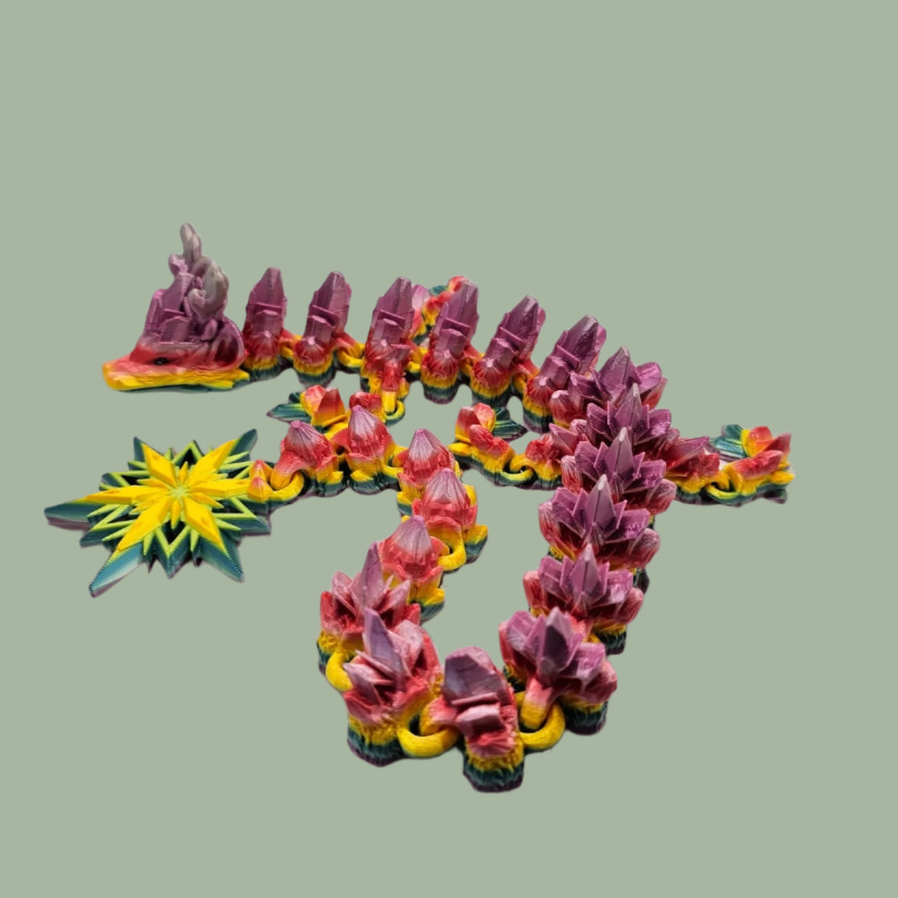 3D printed articulated dragon with snowflake details and large snowflake on tail, in a rainbow colour