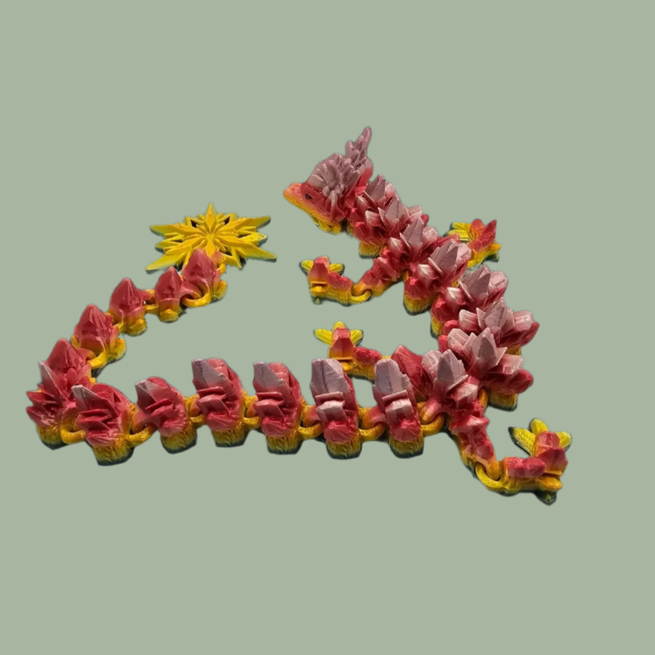 3D printed articulated dragon with snowflake details and large snowflake on tail, in a rainbow colour