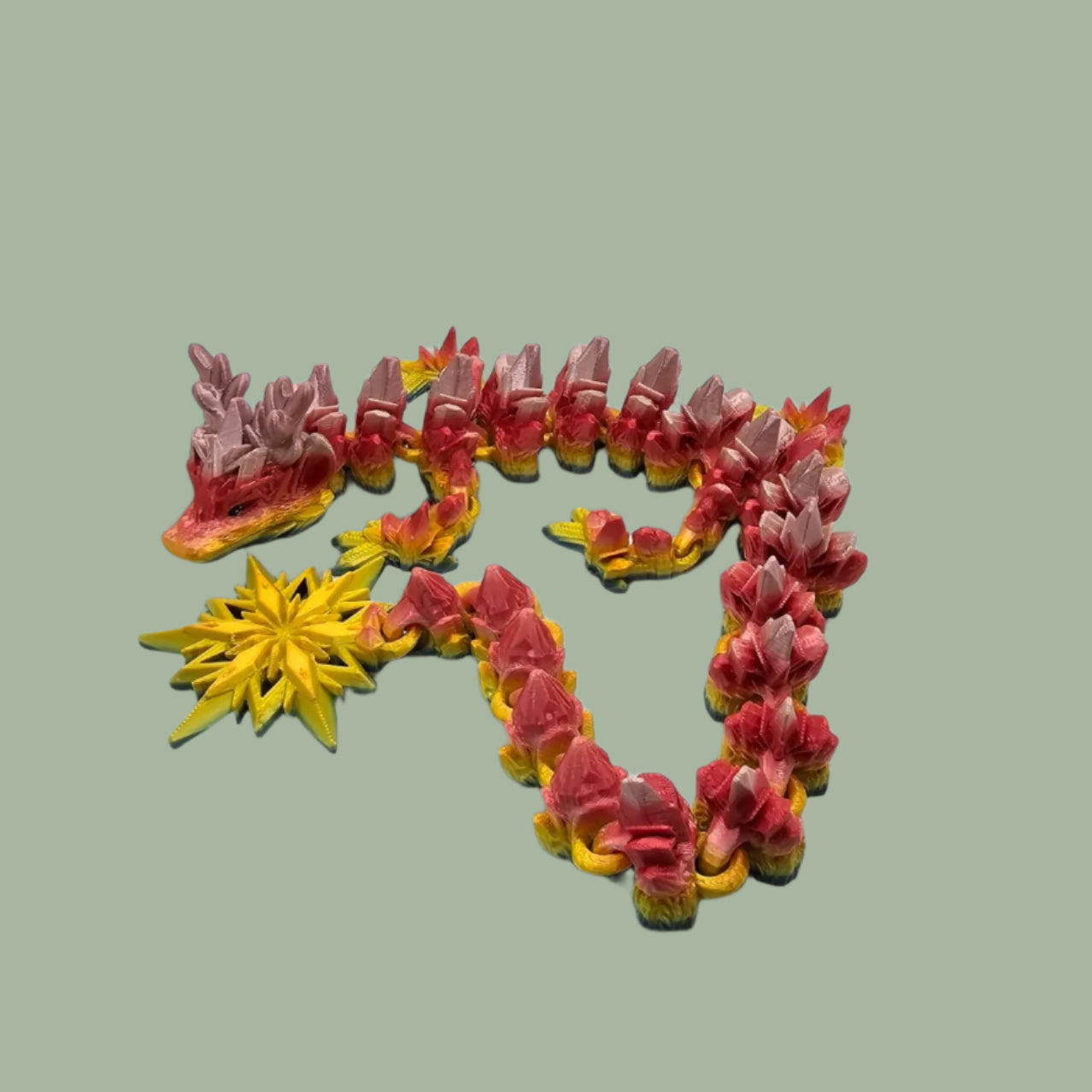 3D printed articulated dragon with snowflake details and large snowflake on tail, in a rainbow colour