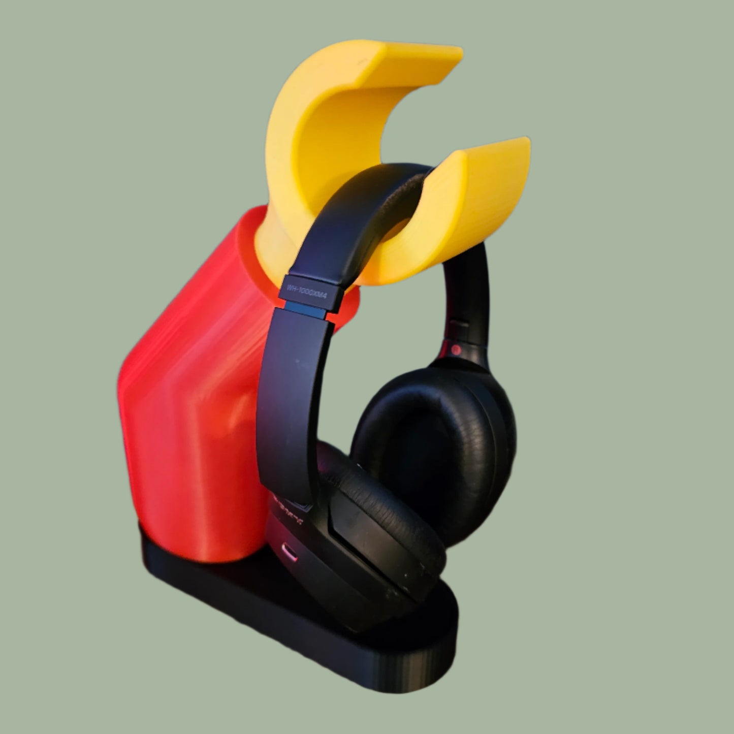 3D printed block style arm in various colours, with black base for wall or freestanding mounting, with chunky yellow hand to hold headphones or coats