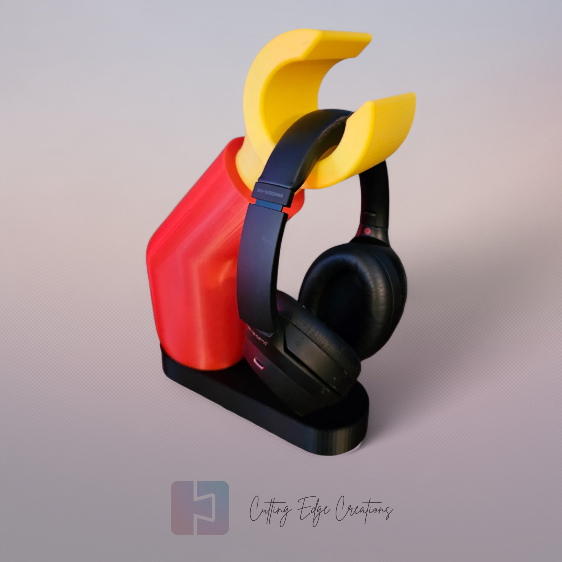 3D printed block style arm in various colours, with black base for wall or freestanding mounting, with chunky yellow hand to hold headphones or coats