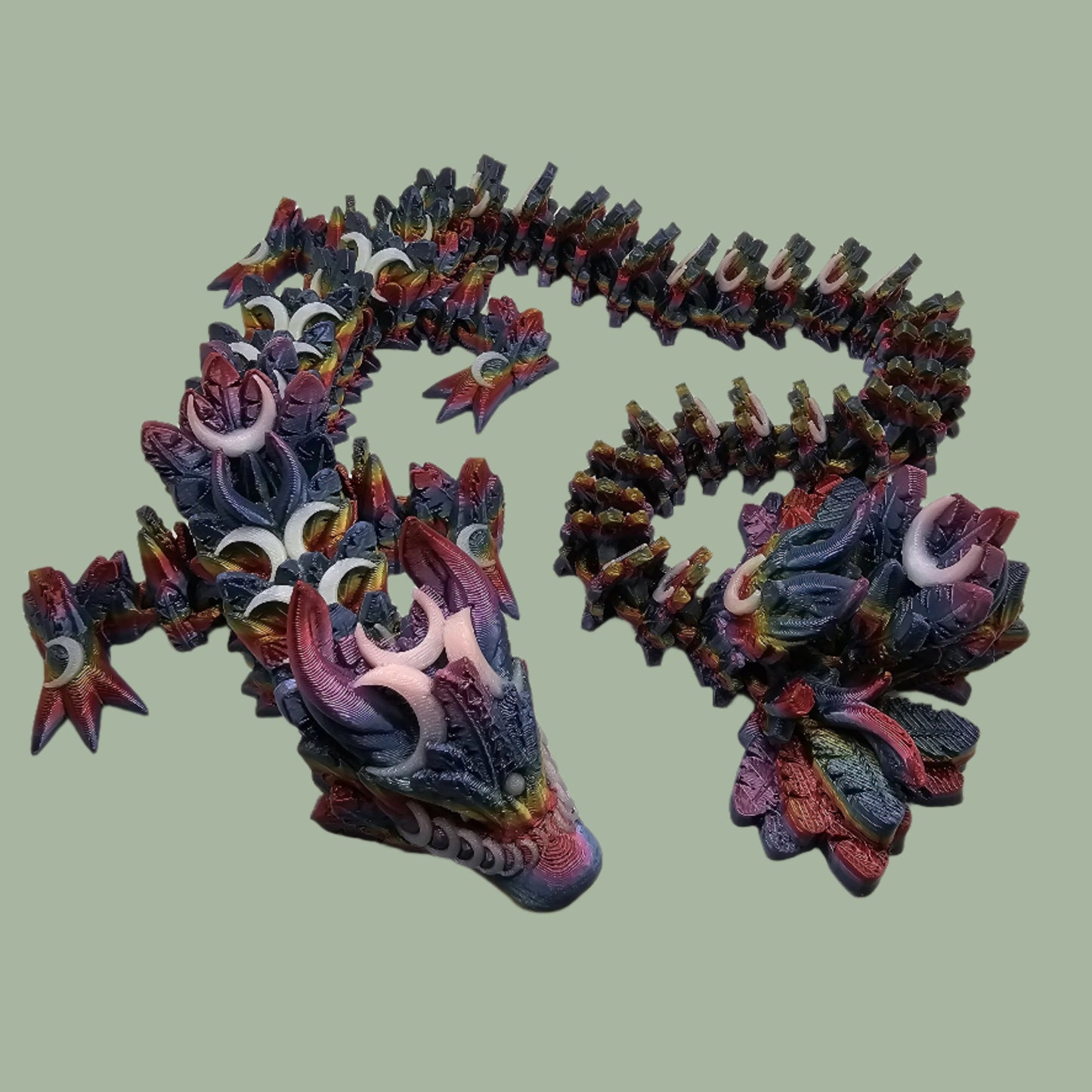 3D printed articulated dragon with crescent moon details, in a dark rainbow colour with glow in the dark moons