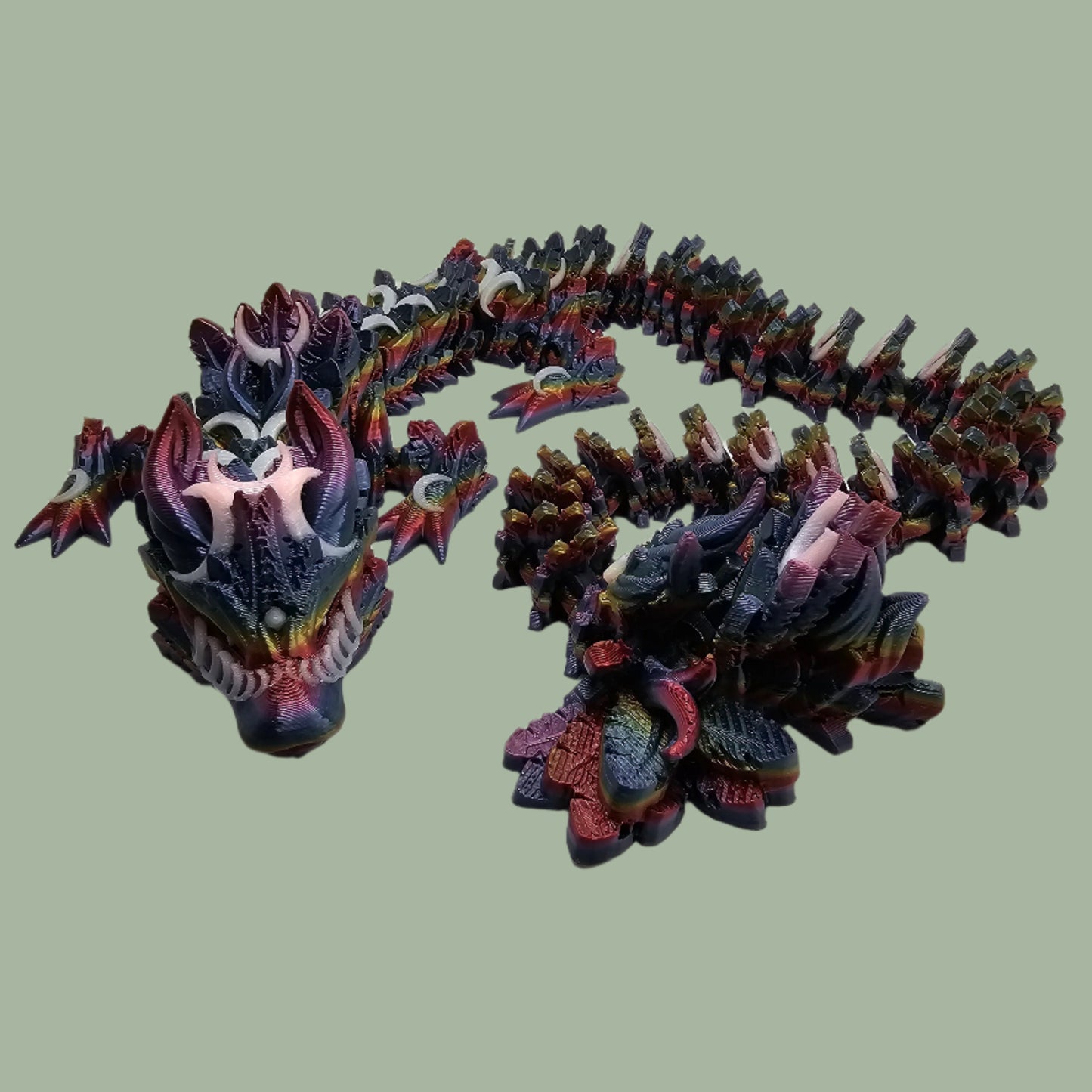 3D printed articulated dragon with crescent moon details, in a dark rainbow colour with glow in the dark moons