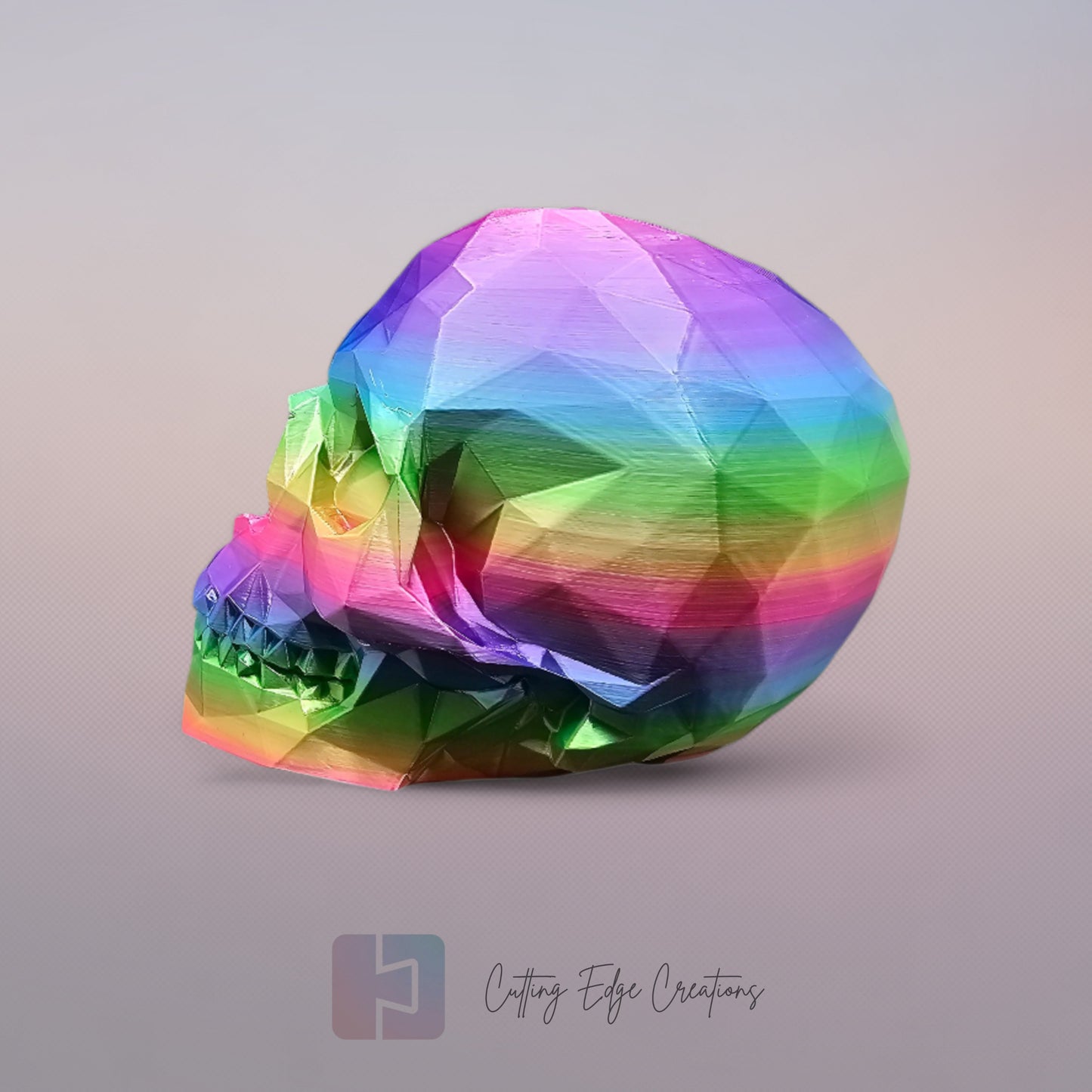 3D-printed low-poly rainbow skull figurine, uniquely coloured with a vibrant gradient. Handmade in the UK, 12cm tall, and perfect for modern home decor or gothic-inspired interiors