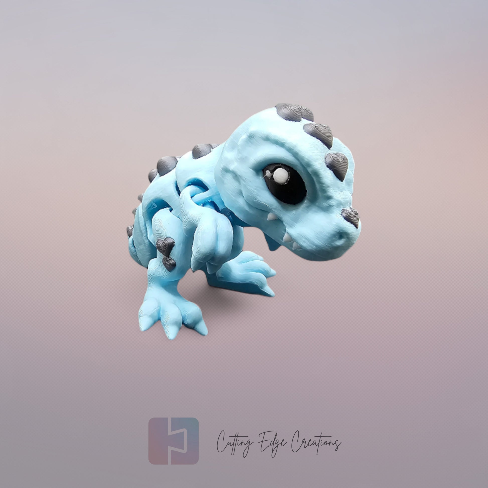 3D printed Love O’Saurus Rex dinosaur toy in light blue with black heart-shaped markings, designed as a flexible and posable fidget toy. Made in the UK by Cutting Edge Creations