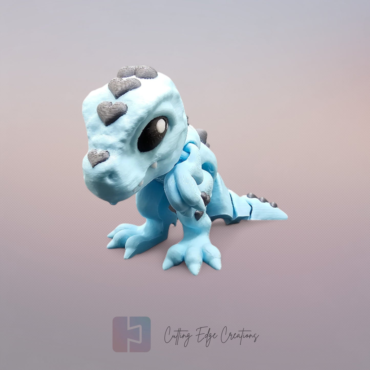 3D printed Love O’Saurus Rex dinosaur toy in light blue with black heart-shaped markings, designed as a flexible and posable fidget toy. Made in the UK by Cutting Edge Creations