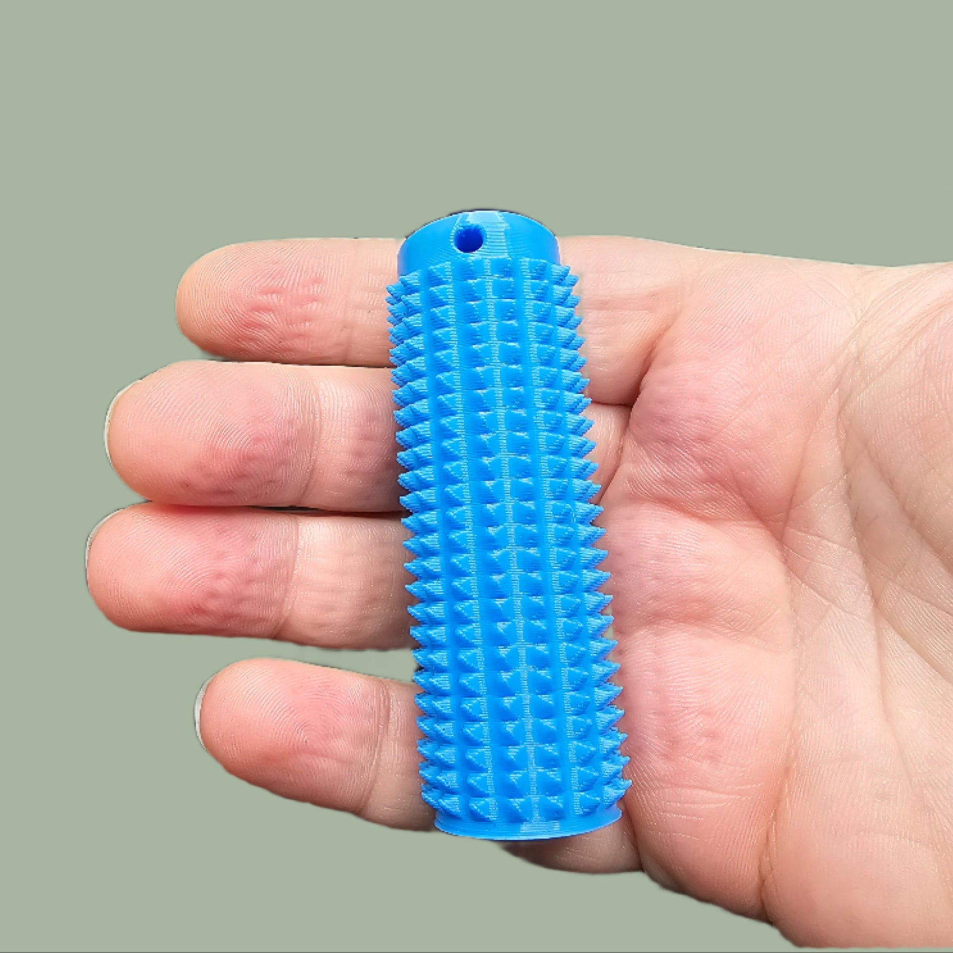 Mini Ouchie Pain Stim – a 7cm long, 3D-printed sensory tool with textured spikes for tactile stimulation, displayed against a neutral background. Includes a keychain for easy portability