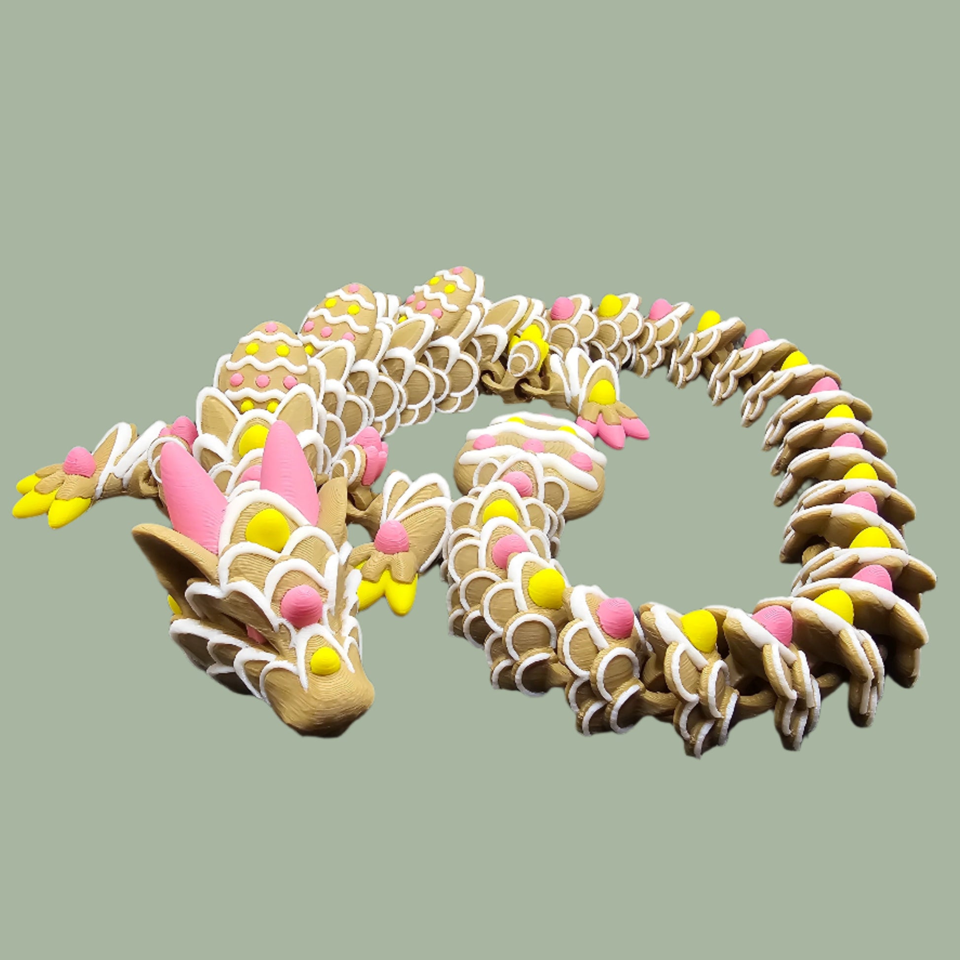 3D-printed Easter Cookie Dragon figurine, designed to resemble a decorated sugar cookie with pastel pink, yellow, and white icing details. Features Easter egg-shaped cookies along its body and tail. Handmade in the UK and available in Medium, Large, and X-Large sizes.