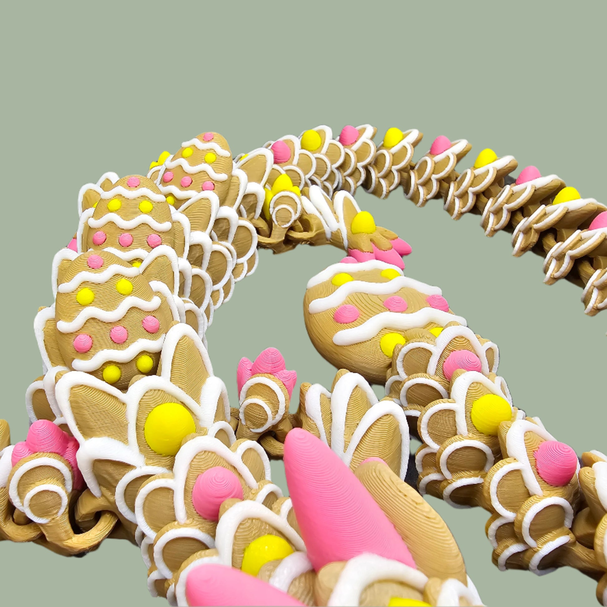 3D-printed Easter Cookie Dragon figurine, designed to resemble a decorated sugar cookie with pastel pink, yellow, and white icing details. Features Easter egg-shaped cookies along its body and tail. Handmade in the UK and available in Medium, Large, and X-Large sizes.