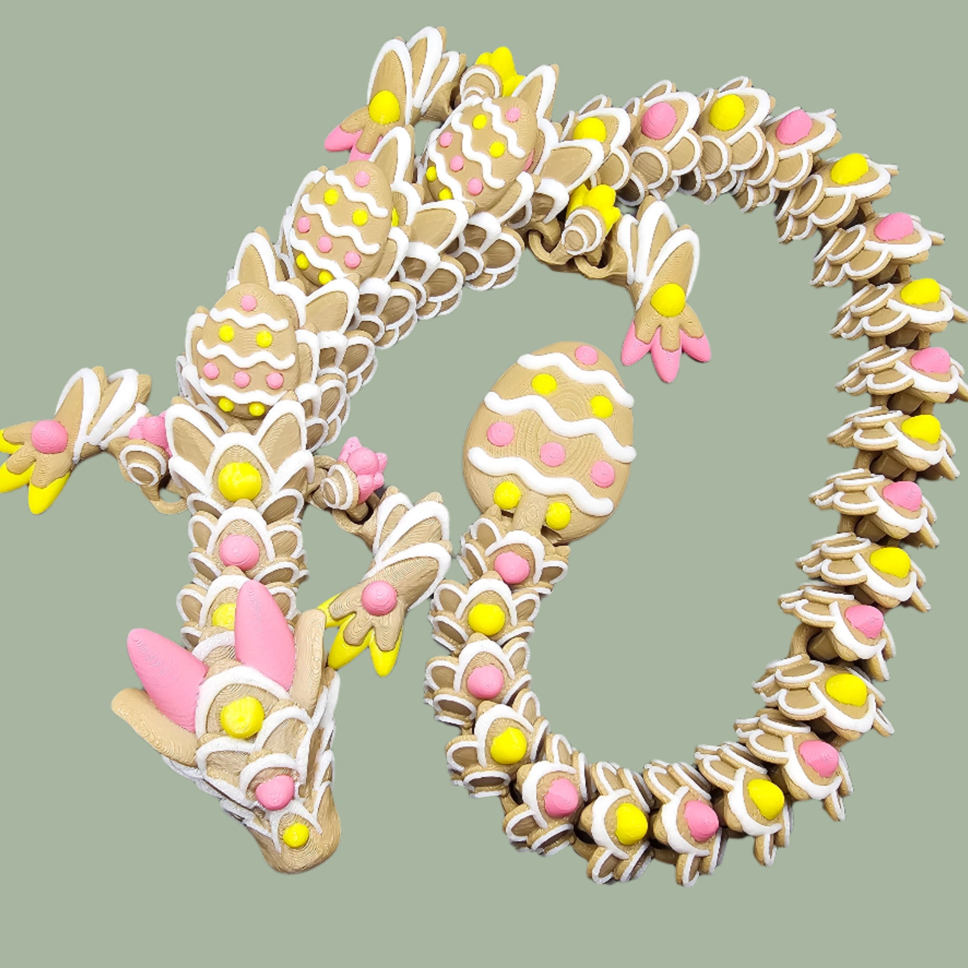 3D-printed Easter Cookie Dragon figurine, designed to resemble a decorated sugar cookie with pastel pink, yellow, and white icing details. Features Easter egg-shaped cookies along its body and tail. Handmade in the UK and available in Medium, Large, and X-Large sizes.