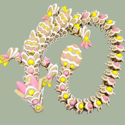 3D-printed Easter Cookie Dragon figurine, designed to resemble a decorated sugar cookie with pastel pink, yellow, and white icing details. Features Easter egg-shaped cookies along its body and tail. Handmade in the UK and available in Medium, Large, and X-Large sizes.