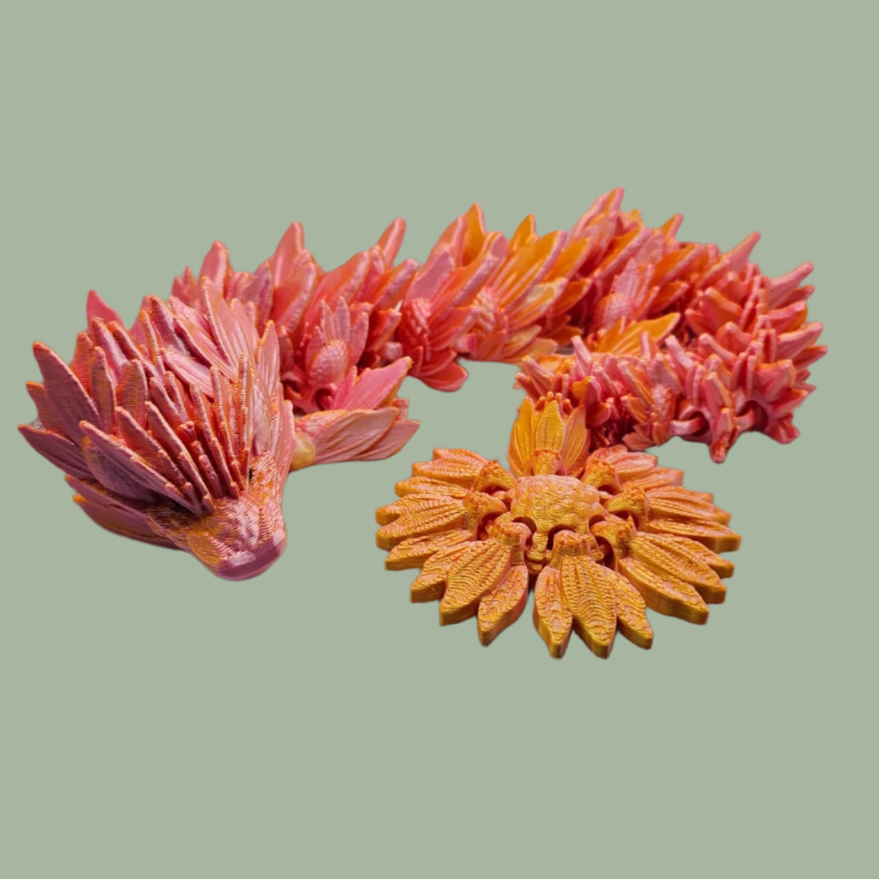 3D printed articulated dragon with sunflower detail, in a orange/pink colour