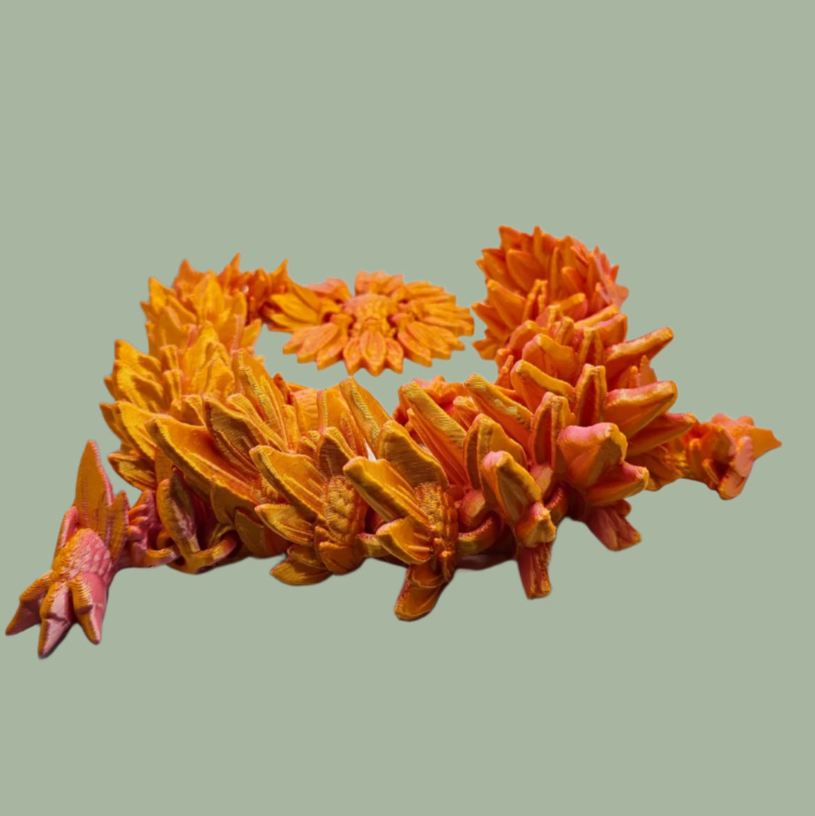 3D printed articulated dragon with sunflower detail, in a orange/pink colour