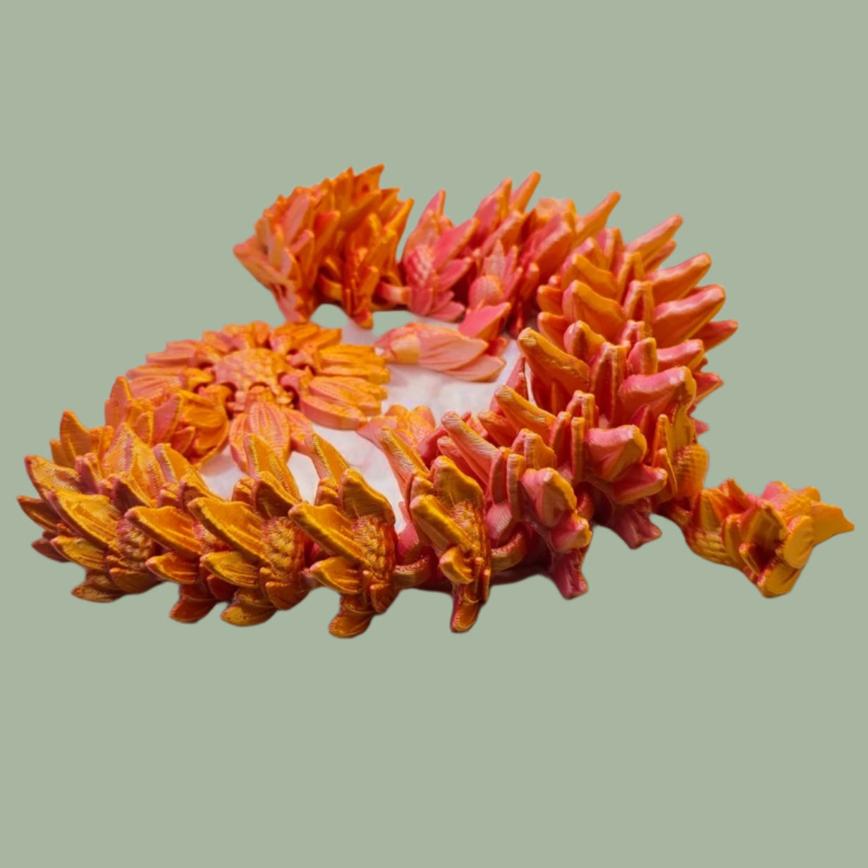 3D printed articulated dragon with sunflower detail, in a orange/pink colour