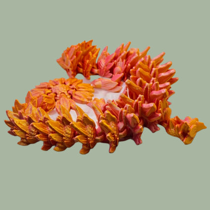 3D printed articulated dragon with sunflower detail, in a orange/pink colour