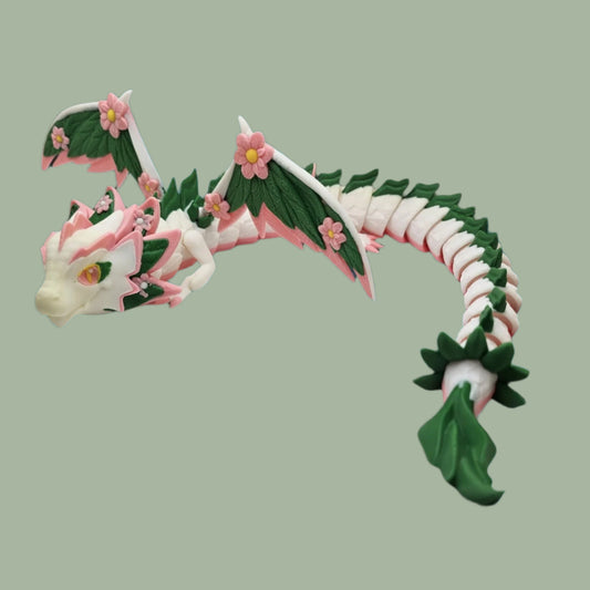 3D printed articulated winged dragon with white body, green leaf details, and pink cherry blossom flower details