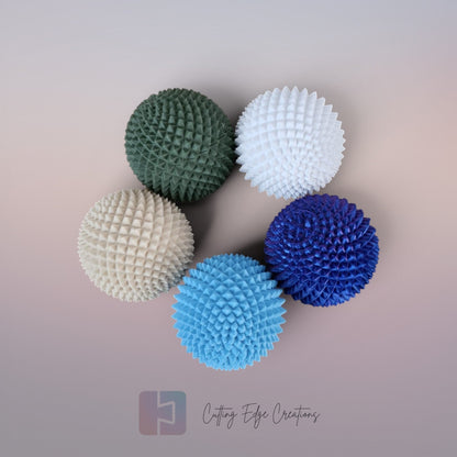 Cutting Edge Creations Spike Sphere fidget toy, 5cm textured polymer ball with micro-spikes in green, white, blue, and cream.