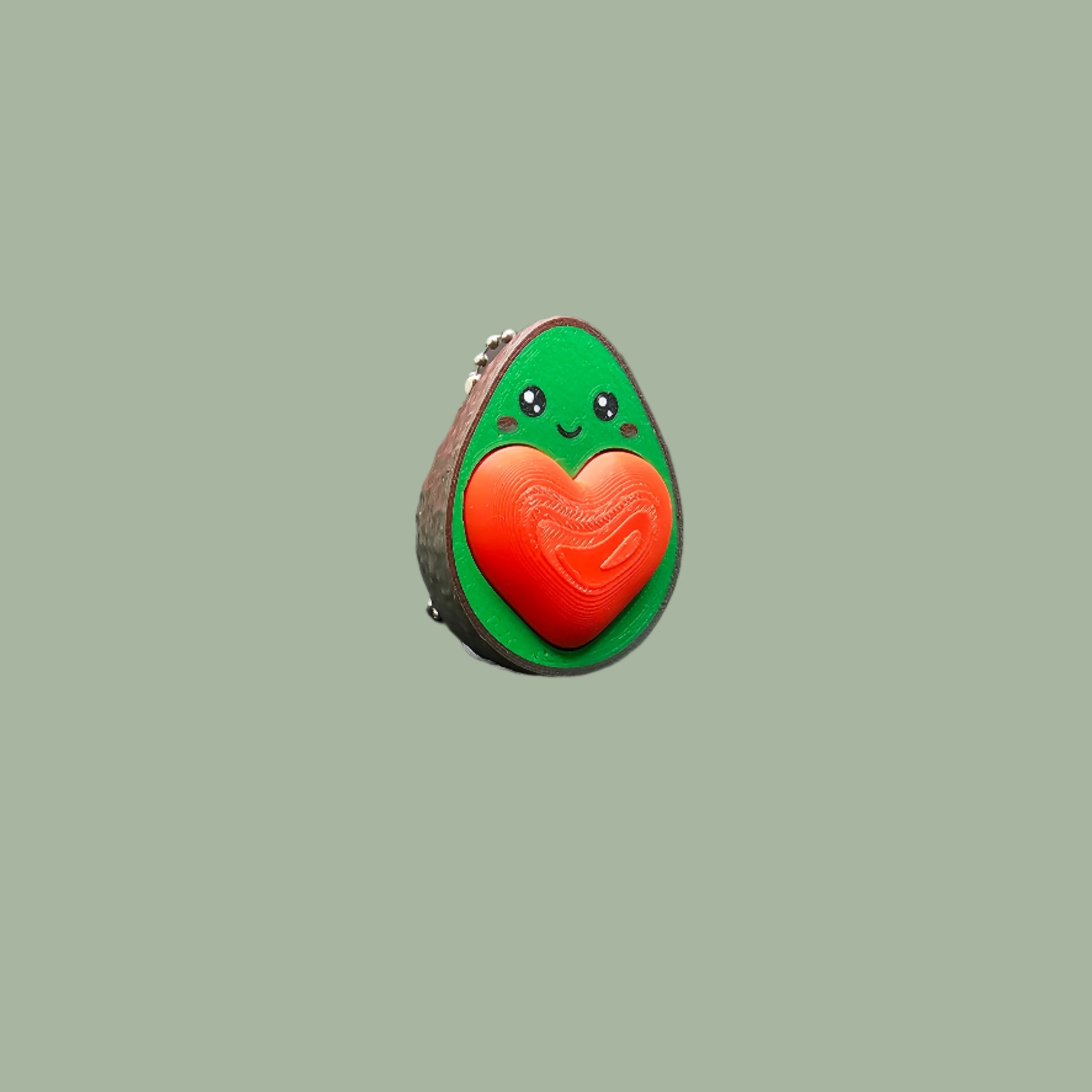 Cute 3D-printed avocado fidget clicker keychain with a heart-shaped clickable stone. Small stress relief toy, 5.5cm tall, made in the UK. Perfect for fidgeting, anxiety relief, and as a fun keyring accessory