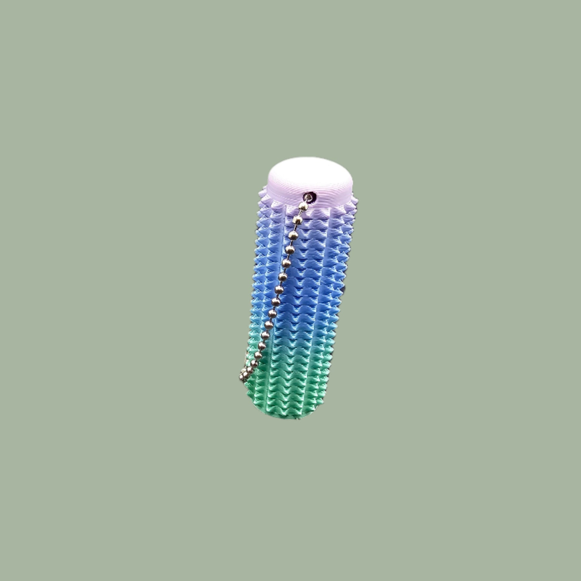 Mini Ouchie Pain Stim – a 7cm long, 3D-printed sensory tool with textured spikes for tactile stimulation, displayed against a neutral background. Includes a keychain for easy portability