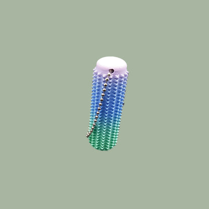 Mini Ouchie Pain Stim – a 7cm long, 3D-printed sensory tool with textured spikes for tactile stimulation, displayed against a neutral background. Includes a keychain for easy portability
